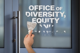 A person is scraping text that says “Office of Diversity, Equity and Inclusion”  from a door.